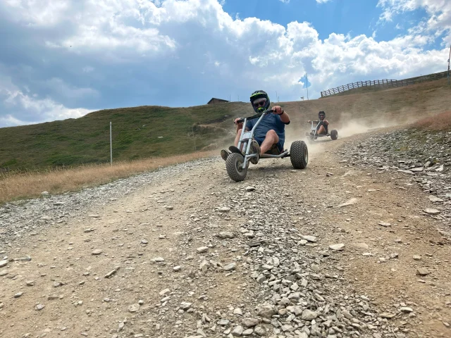 le Mountain Kart est un engin tout terrain à trois roues (deux grosses à l’arrière une plus petite devant), avec un guidon, deux freins indépendants (ce qui rend la conduite assez technique), deux emplacements pour poser les pieds et pas de moteur comme vous pourriez en trouver sur un kart normal. Il n’y a pas de pédales non plus car le Mountain Kart ne se pratique qu’en descente.